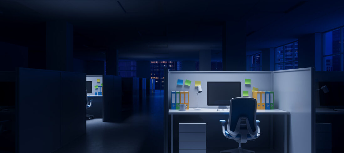 Office cubicle with glowing workstation in dark corporate interior at night, concept of overtime or late-night productivity in modern workplace. 3D Rendering